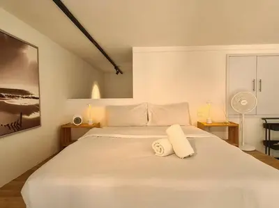 a white bedroom with a large white bed with two towels at SkyView Studio, EST Bangsar, High View for 2 in Kuala Lumpur