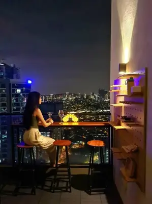 a woman sitting at a bar on top of a building at SkyView Studio, EST Bangsar, High View for 2 in Kuala Lumpur