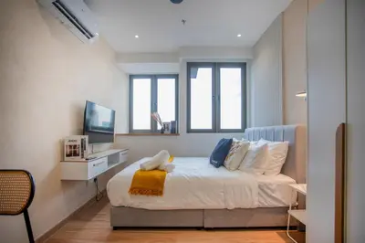 a bedroom with a bed and a tv and windows at Riveria City near KL Sentral with 118 view Sky Infinity Pool by COBNB in Kuala Lumpur