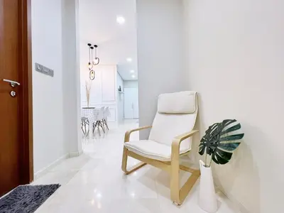 a white chair in a hallway with a potted plant at Sky Suites Airy 2BR Suite at KLCC in Kuala Lumpur