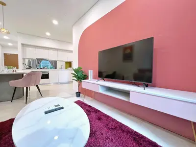 a living room with a large red wall with a tv at Sky Suites Blush 3BR Suite at KLCC in Kuala Lumpur