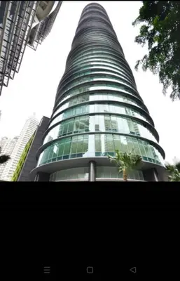 a tall glass building with a tree in front of it at KL Suites Apartment at Vortex in Kuala Lumpur
