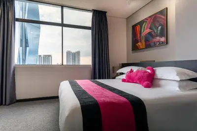 a pink teddy bear laying on a bed in a hotel room at TEEDO Hotel Kuala Lumpur in Kuala Lumpur