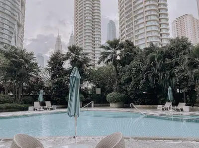 a swimming pool with chairs and an umbrella in a city at Deluxe Family Suites w KLCC View in Kuala Lumpur