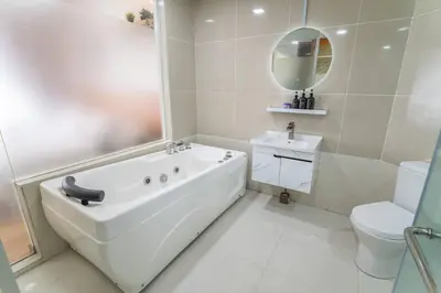a white bathroom with a tub and a toilet at Relaxing Muji Retreat with Jacuzzi, Retro Games, MRT in Kuala Lumpur