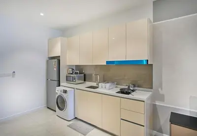 a kitchen with white cabinets and a washer and dryer at Quill Residence Luxury Suite Kuala Lumpur by Cobnb in Kuala Lumpur