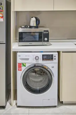 a microwave sitting on top of a washing machine at Quill Residence Luxury Suite Kuala Lumpur by Cobnb in Kuala Lumpur