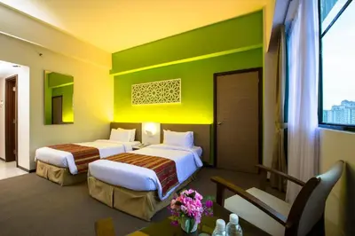 two beds in a hotel room with green and yellow walls at Grand Barakah Hotel in Kuala Lumpur
