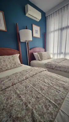 two beds in a bedroom with blue walls and a window at KLCC Legasi Executive Suite Apartment in Kuala Lumpur