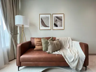 a living room with a brown couch with pillows at Sky Suites Charming 3BR Suite KLCC View in Kuala Lumpur