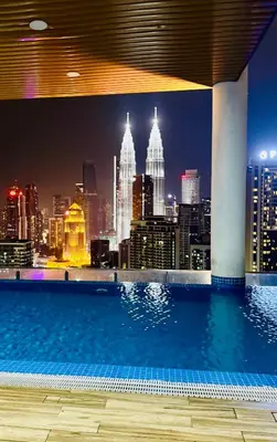 a swimming pool with a city skyline at night at KIcc view residences by the colony in Kuala Lumpur