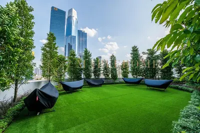 a garden with blue chairs on a green lawn at Agile Premier Suites Kuala Lumpur in Kuala Lumpur
