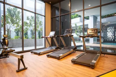 a gym with three treadmills in a room with windows at Neu Suites By Cozy Unit L30RA 2-3PAX near KLCC & Jelatek LRT in Kuala Lumpur