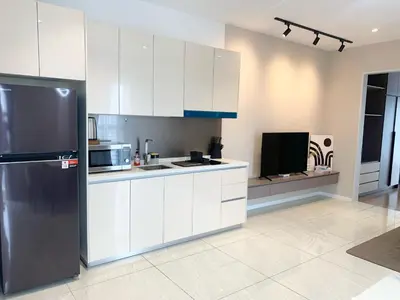 a kitchen with white cabinets and a black refrigerator at Quill Residences Service Suites By BR in Kuala Lumpur