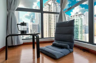 a chair and a table in a room with a large window at Spacious Family Apt 3-Min Walk to KLCC MRT RO Water Baby Crib Home Cinema Projector in Kuala Lumpur