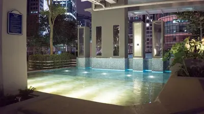 a building with a swimming pool in a city at night at Spacious Family Apt 3-Min Walk to KLCC MRT RO Water Baby Crib Home Cinema Projector in Kuala Lumpur