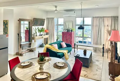 a living room with a table and red chairs at 3 bedroom apt L21 in kl sentral with city view in Kuala Lumpur