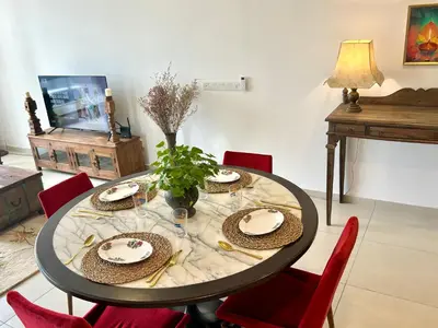 a dining room table with red chairs and a table with plates at 3 bedroom apt L21 in kl sentral with city view in Kuala Lumpur
