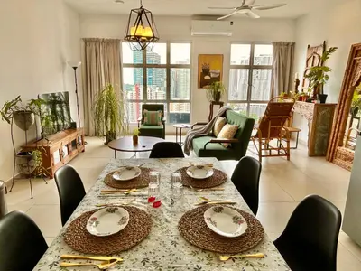 a dining room with a table and chairs and a living room at 3 bedroom apt L26 at kl sentral with city view in Kuala Lumpur