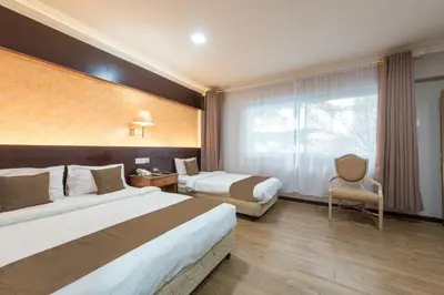 a hotel room with two beds and a chair at Hotel grand orchard in Kuala Lumpur