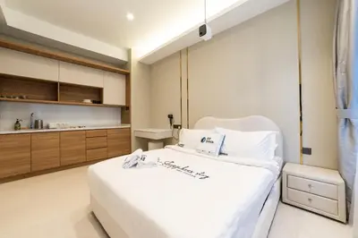 a bedroom with a white bed and a kitchen at Novo Ampang KL near Gleneagles by Sleepy Bear in Kuala Lumpur
