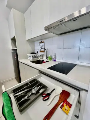 a kitchen with white cabinets and a sink and scissors at The Luxe Stay Chamber KL in Kuala Lumpur