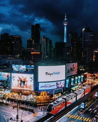 a city at night with a train and billboards at Hi\u8212\u9002\u5927\u5e8a\u623f klcc\u65c1 \u8f7b\u8f68\u65c1 \u65e0\u8fb9\u6e38\u6cf3\u6c60 in Kuala Lumpur