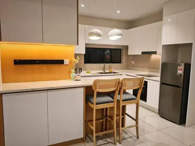 a kitchen with a counter with two chairs and a refrigerator at 4B3R Lux Penthouse Astoria Ampang in Kuala Lumpur