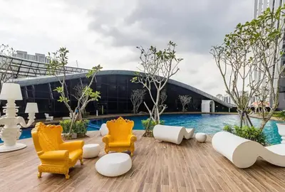 a pool with yellow chairs and chairs next to a building at Arte Mont Kiara Wonder 2BR Suites in Kuala Lumpur