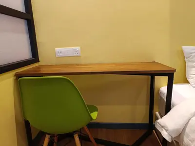 a green desk with a green chair next to a bed at Fahrenheit 88 in Kuala Lumpur
