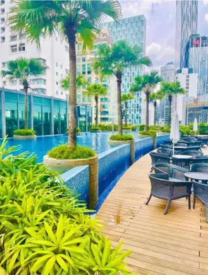 a swimming pool with tables and palm trees on a building at VORTEX SUITS KLCC by MMHB in Kuala Lumpur