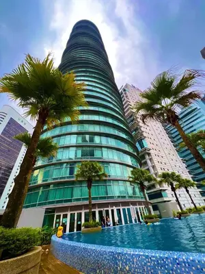 a tall building with palm trees in front of it at Vortex Suites Klcc Area in Kuala Lumpur