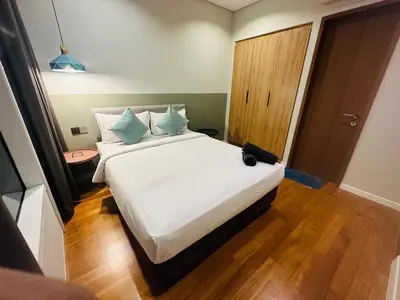 a bedroom with a bed with white sheets and blue pillows at Vortex Suites Klcc Area in Kuala Lumpur