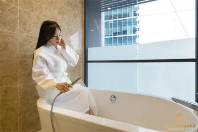 a woman sitting on a toilet while talking on a cell phone at Dorsett Kuala Lumpur, Five Senses in Kuala Lumpur