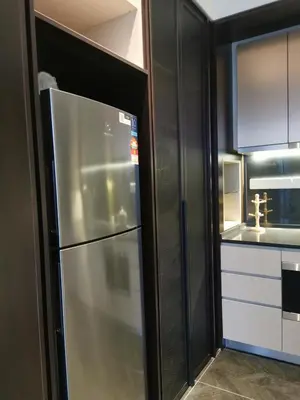 a stainless steel refrigerator in a kitchen with black cabinets at Scarletz Suites KLCC by De Harlequins Suite in Kuala Lumpur
