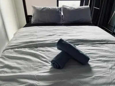 a blue towel sitting on top of a bed at Neu Suites Cozy Family House KLCC in Kuala Lumpur