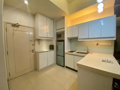 a kitchen with white cabinets and a sink and a refrigerator at Parkview Serviced Apartment in Kuala Lumpur