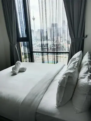 a bed with pillows in front of a large window at OPUS LUXURY INFINiTY POOL KL in Kuala Lumpur