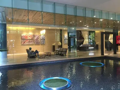 a man sitting in a chair next to a swimming pool at M CITY 2 Bed KLCC BY D in Kuala Lumpur