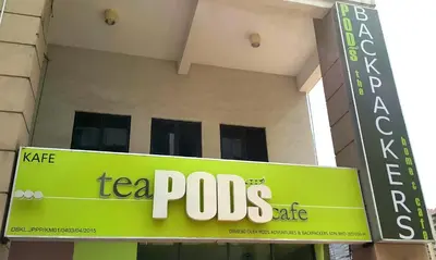 a sign in front of a building with a tea pots cafe at PODs The Backpackers Home & Cafe, Kuala Lumpur in Kuala Lumpur
