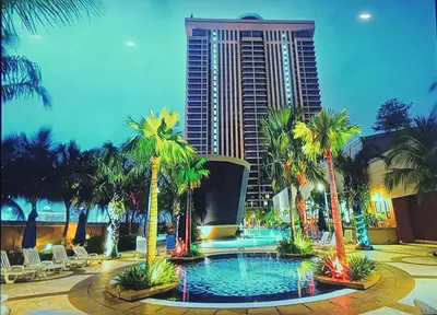 a resort with a pool with palm trees and a building at KL Cozy Suite Apartment At Times Square in Kuala Lumpur