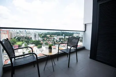 a balcony with a table and chairs and a large window at Bangsar Signature By PSM in Kuala Lumpur
