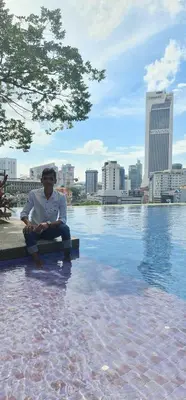 a man sitting on a bench next to a body of water at THE ROBERSTSON RESIDENT WITH VIEW Kuala Lumpur in Kuala Lumpur