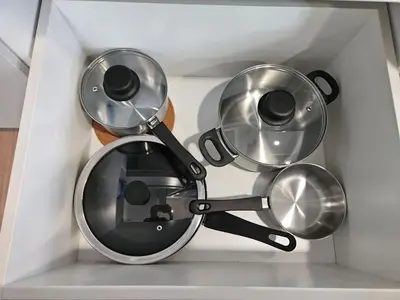 a group of pots and pans in a white drawer at SerenityStayatRiveria KL Sentral in Kuala Lumpur
