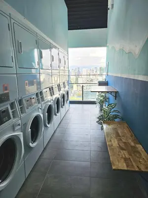 a laundry room with multiple washing machines and a table at SerenityStayatRiveria KL Sentral in Kuala Lumpur