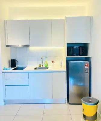 a kitchen with white cabinets and a stainless steel refrigerator at Chambers Kl by MRJ in Kuala Lumpur