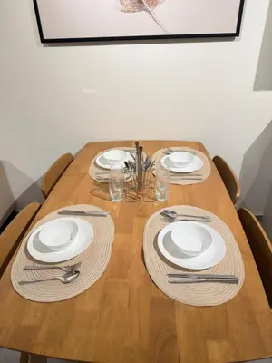 a wooden table with white plates and silverware on it at Agile Bukit Bintang by SOD in Kuala Lumpur