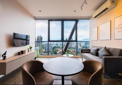 a living room with a table and chairs and a large window at Scarletz Suites KLCC by WSD in Kuala Lumpur