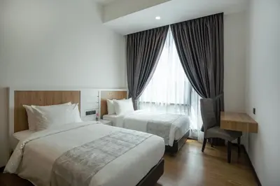 a hotel room with two beds and a desk and a window at Luxe Suite in Kuala Lumpur