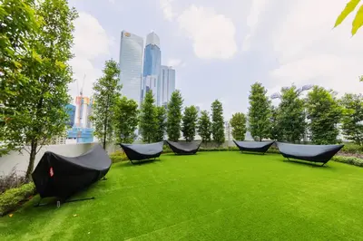 a group of chairs on a green lawn with a city at Agile Bukit Bintang TRX Pavilion KL by WSD in Kuala Lumpur